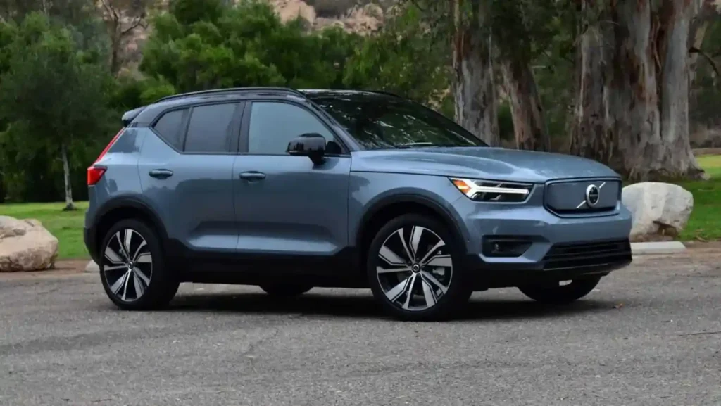 볼보 EX40 전기 SUV 측면 정면 이미지, 블루 그레이 컬러와 자연 배경