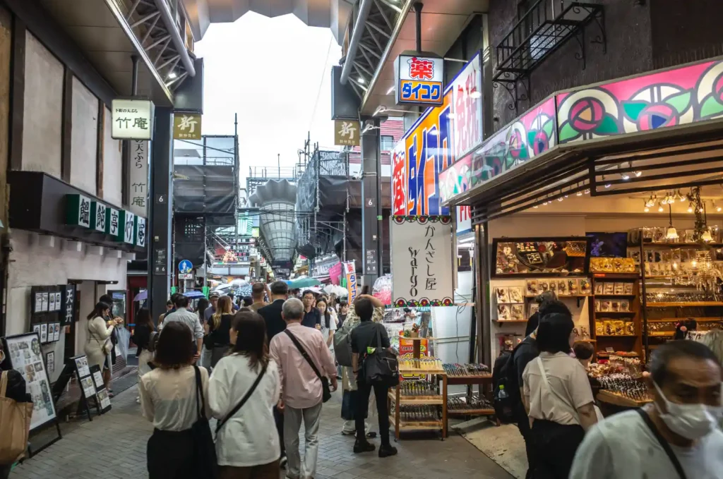 아사쿠사역에서 센소지로 가는 상점가 거리. 전통 초롱이 천장에 걸려 있고, 양옆으로 기념품 가게와 식당들이 늘어서 있으며, 관광객들이 센소지 방향으로 걸어가는 모습