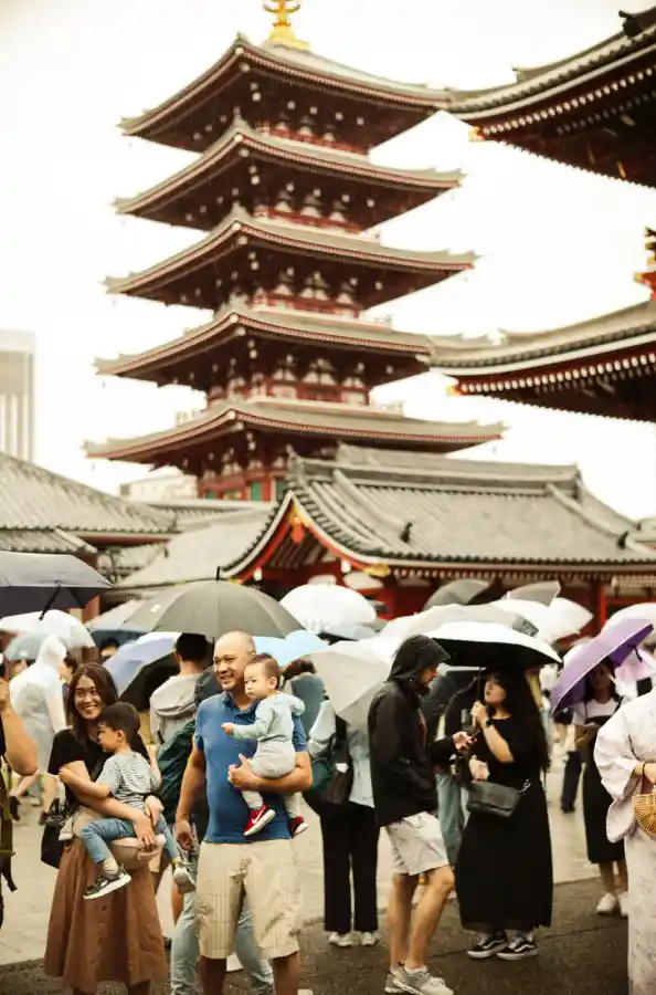 센소지 5층탑과 본당 전경. 높이 48m의 5층 목탑이 중앙에 우뚝 솟아 있고, 양옆으로 붉은 지붕의 전통 건축물들이 보이며, 비 오는 날 우산 든 관광객들이 광장을 가득 메우고 있는 모습. 회색 하늘을 배경으로 한 센소지의 장엄한 풍경