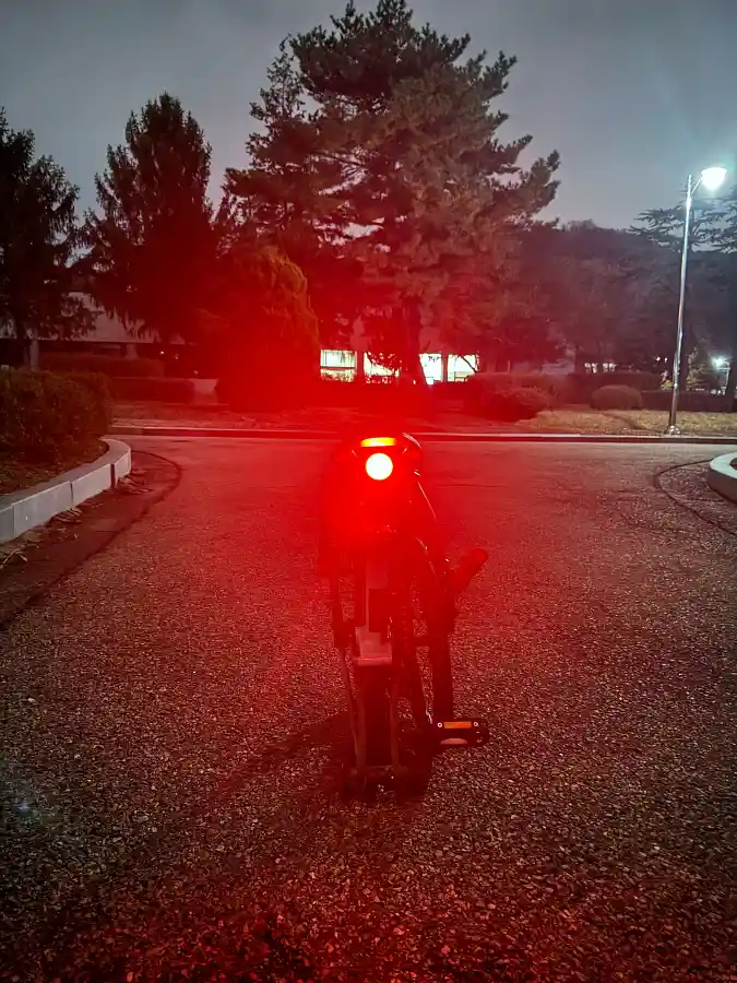 황혼 무렵 접혀진 브롬톤 뒤에서 본 모습, RAZ 라즈 프로 후미등이 붉은 빛을 비추고 있음