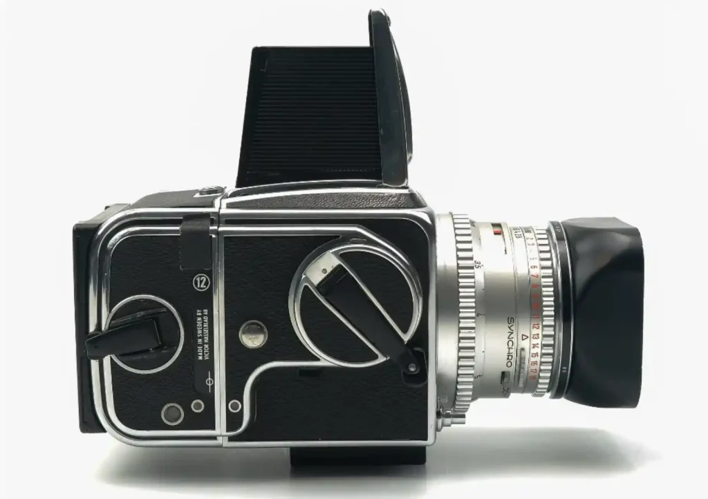 핫셀블라드 500C/M 중형 필름 카메라의 측면 모습. 실버 크롬 마감의 바디에 칼 자이스 Synchro-Compur 렌즈가 장착되어 있고 상단의 웨이스트 레벨 파인더가 열려 있으며 필름 백에 12컷 표시가 보이는 클래식 제품 사진