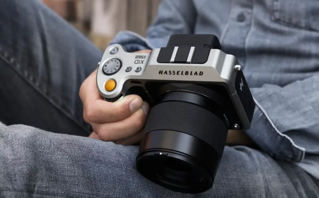 핫셀블라드 X1D-50c 실버 모델을 사용자가 손에 쥐고 있는 측면 사진. 날렵한 금속 바디와 깊은 그립부가 돋보인다.