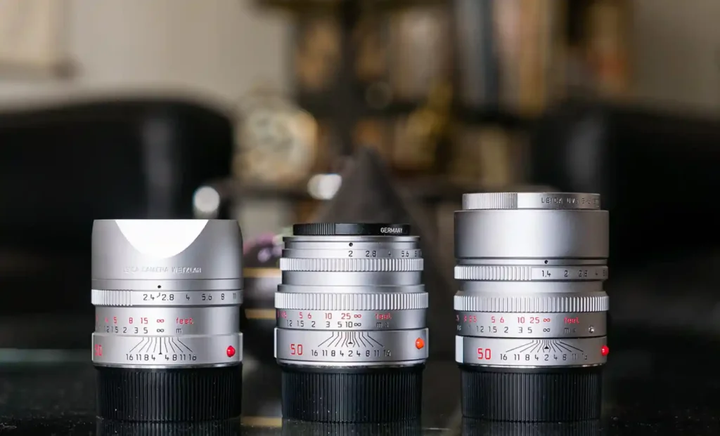 세대가 다른 라이카 실버 크롬 M 렌즈 세 개가 나란히 놓여 있으며, 조리개 링과 거리계 각인이 일관된 디자인 언어를 보여주는 사진