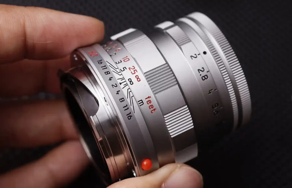 라이카 M 렌즈의 조리개 링을 손가락으로 조작하는 모습으로, 금속 링의 촉감과 클릭감이 잘 드러나는 근접 사진