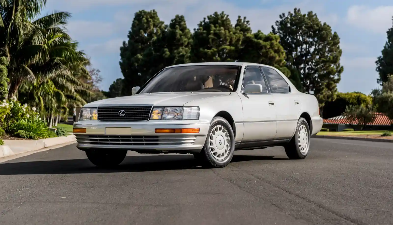 1989년형 렉서스 LS400 초기 모델, 실버 색상의 고급 세단이 야자수와 주택가를 배경으로 도로에 서 있다