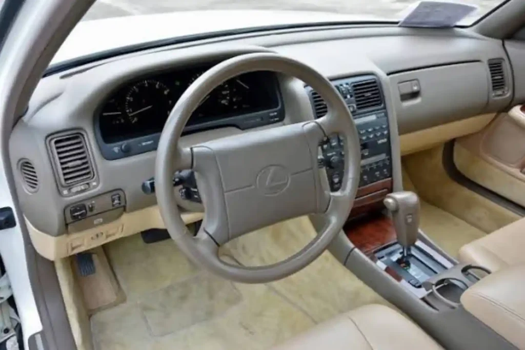 렉서스 LS400 초기 모델 실내, 베이지 가죽 시트와 우드 트림, 렉서스 로고가 새겨진 스티어링 휠과 고급스러운 센터콘솔