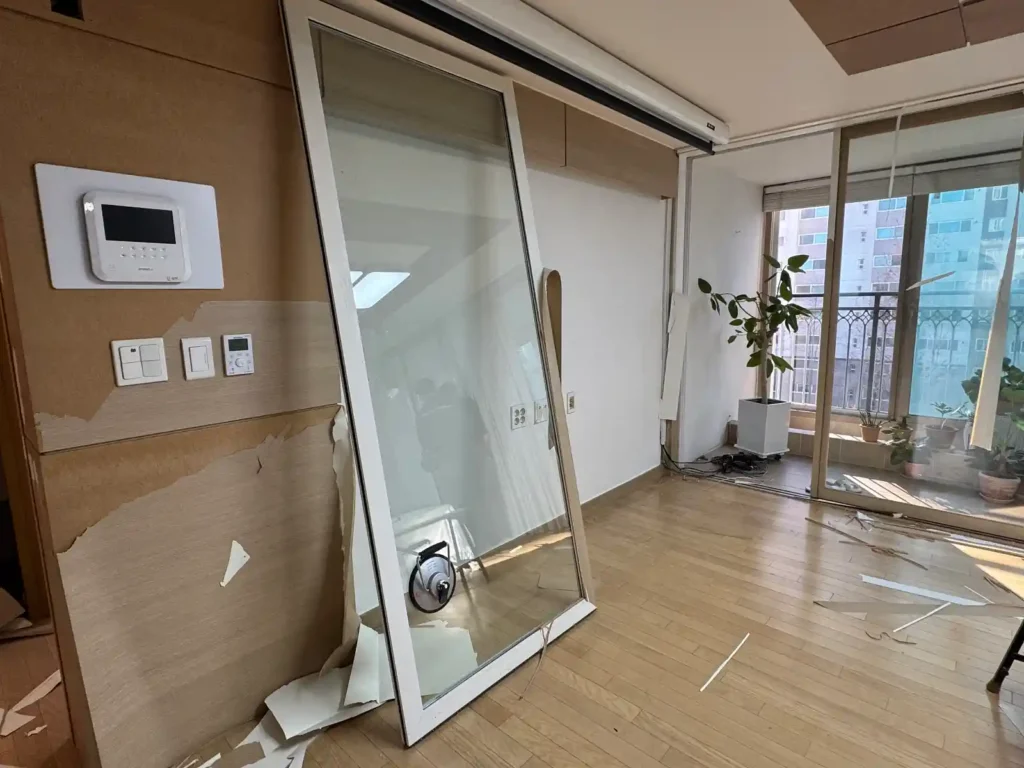 거실 리모델링 공사 현장 - 도배 제거 중인 벽면과 바닥재 작업 준비, 20년 거주 아파트 인테리어 공사