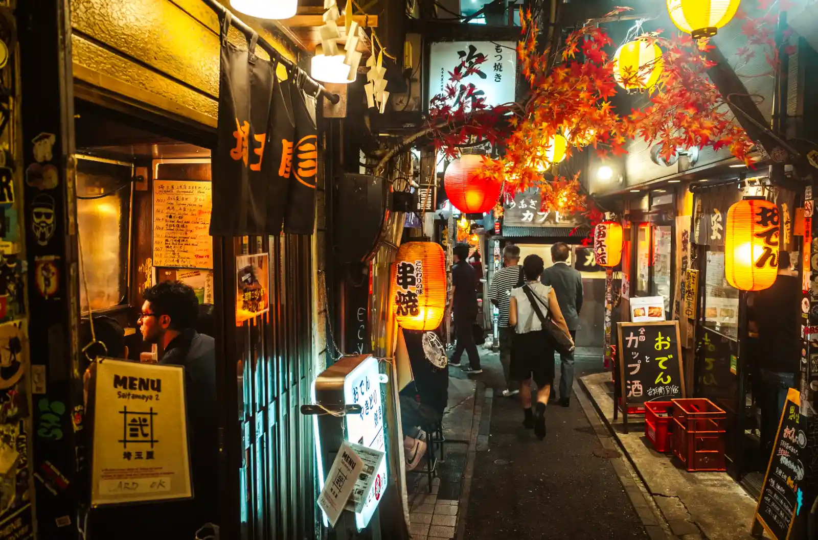 신주쿠 오모이데요코초의 밤 풍경, 노란 초롱불과 붉은 단풍 장식 아래 좁은 골목을 오가는 사람들과 이자카야가 이어진 모습