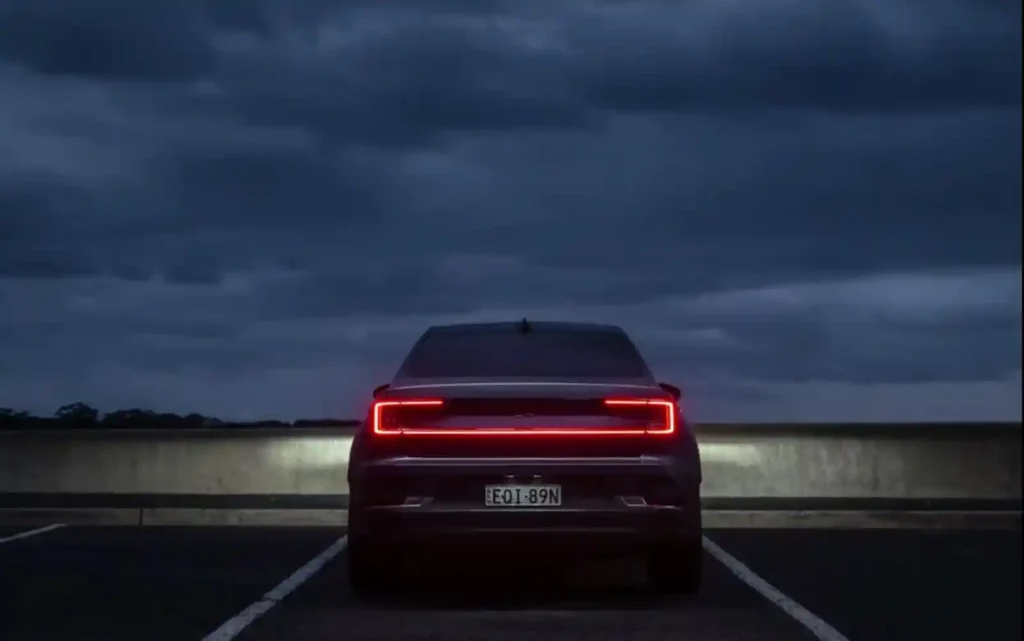 어두운 하늘 아래 주차된 폴스타 2의 뒷모습. 전기차 시장의 불확실한 현실을 상징적으로 보여주는 장면.