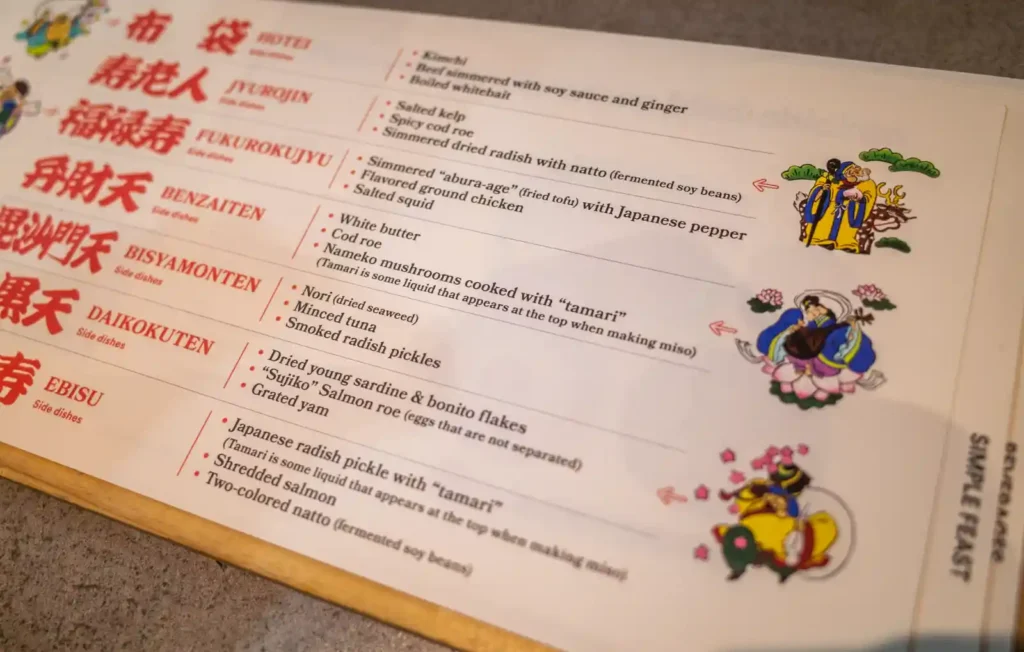 우메토호시 칠복신 메뉴판. 왼쪽에 칠복신 이름이 한자와 영문으로 적혀 있고, 오른쪽에 각 세트의 반찬 구성이 영문으로 나열되어 있다. BENZAITEN 세트에는 White butter, Cod roe, Nameko mushrooms가 포함되어 있으며, 오른쪽에 칠복신을 형상화한 컬러 일러스트가 그려져 있다.