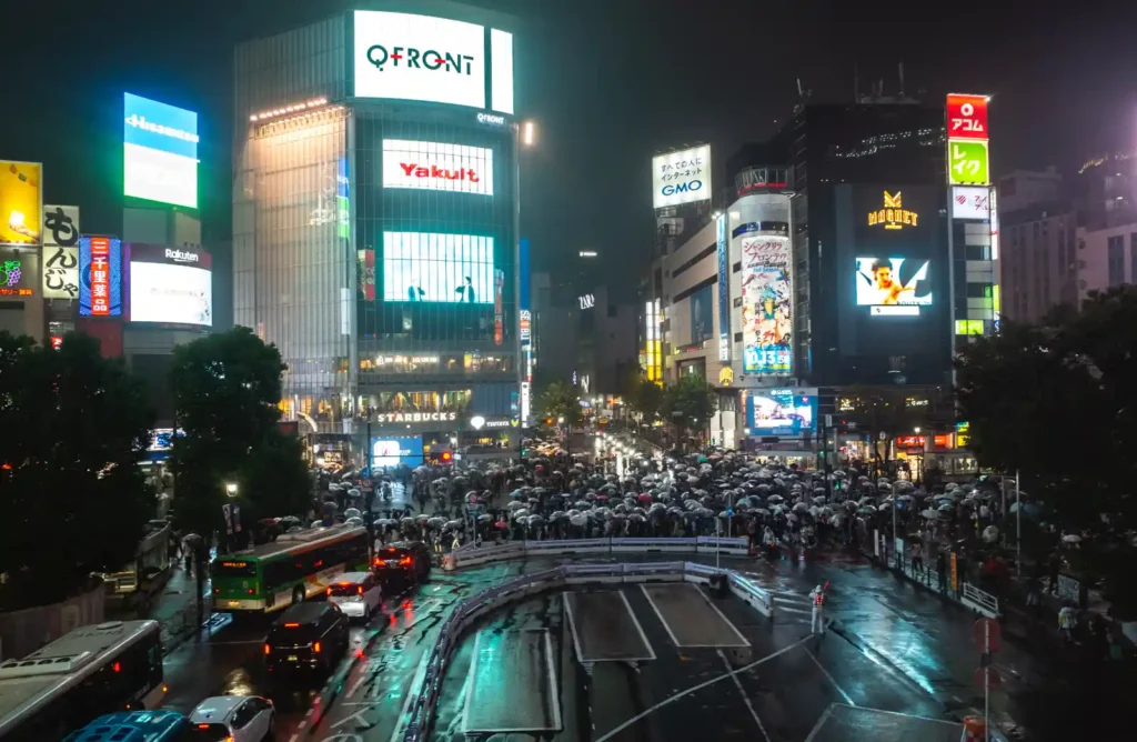 비 오는 밤 시부야 스크램블 교차로를 건너는 수많은 사람들 전경