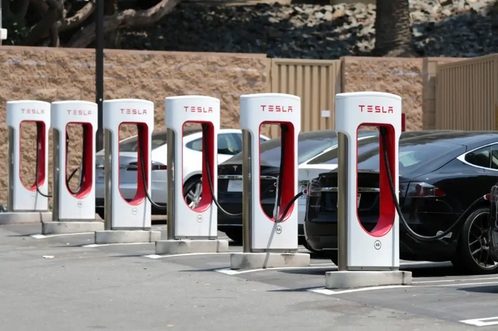 테슬라 슈퍼차저 충전소 - 6대의 충전기가 설치되어 있고 여러 대의 테슬라 차량이 충전 중인 모습