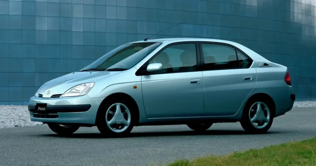 1997년 토요타 프리우스 1세대 모델. 세계 최초 양산형 하이브리드 자동차로 실버 색상의 4도어 세단 형태. 1.5L 엔진과 전기모터를 결합해 리터당 28km의 혁신적인 연비를 달성했다