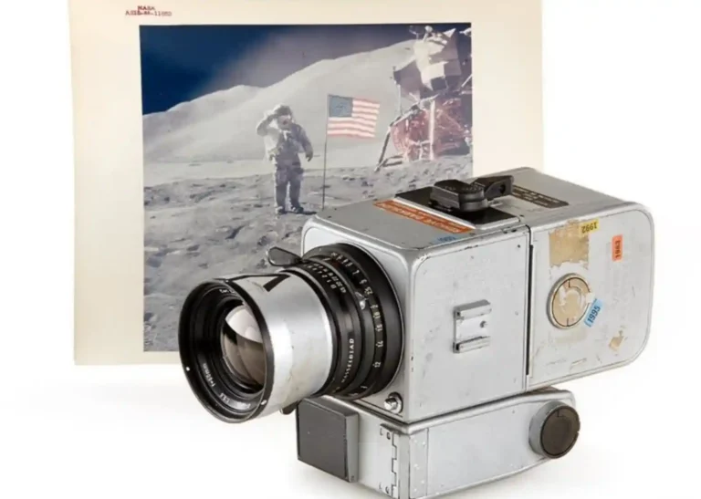 NASA 아폴로 계획에 사용된 실버 색상의 핫셀블라드 500EL 카메라와 칼 자이스 렌즈, 배경에는 이 카메라로 촬영된 달 표면 착륙 장면