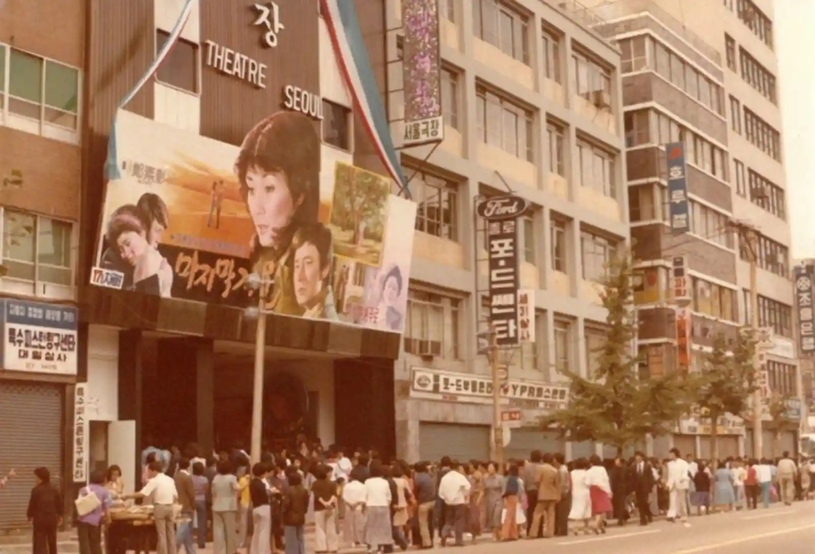 1990년대 초반 서울의 한 극장 앞에 영화를 보기 위해 길게 줄 서 있는 관객들. THEATRE SEOUL 간판이 보이는 극장 건물과 당시 거리 풍경을 담은 빈티지 사진