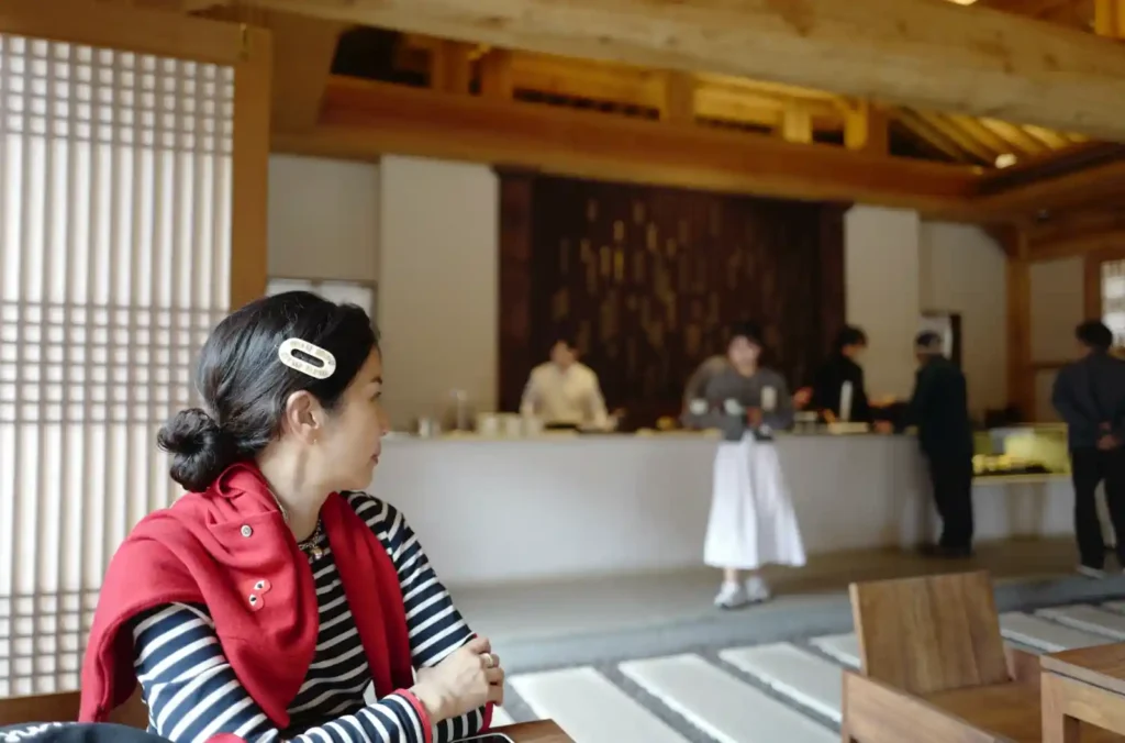 Leica Q 28mm f/1.7로 촬영한 실내 환경 인물 사진, 전경 인물은 또렷하고 카페 공간이 함께 담긴 광각 예시