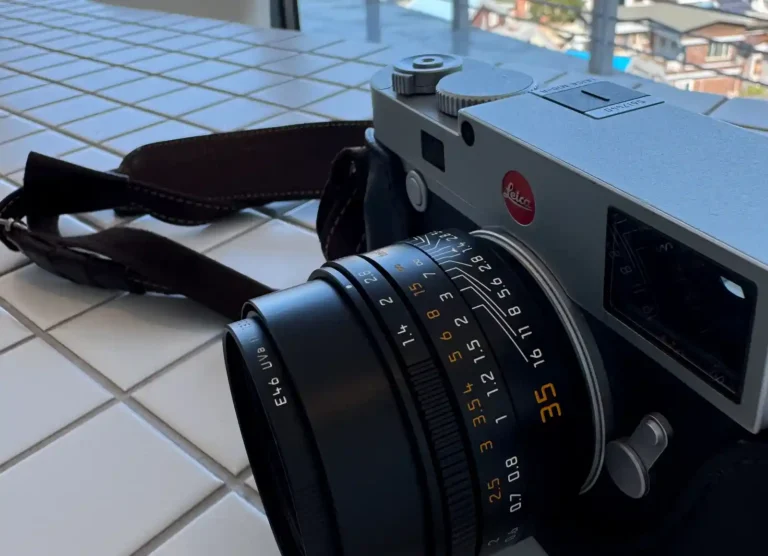 라이카 M10 실버 크롬 바디에 장착된 주미룩스 35mm f/1.4 렌즈 - 테이블 위에 놓인 측면 각도