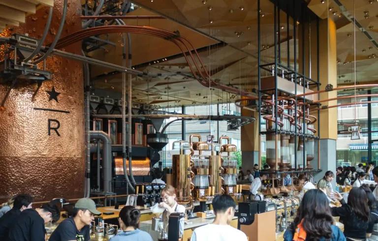 도쿄 나카메구로 스타벅스 리저브 로스터리 내부 전경, 구리 로스팅 탱크와 파이프 설비, 브루잉 바에서 음료를 준비하는 바리스타 모습