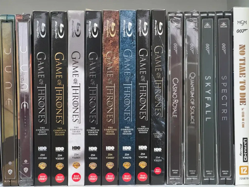 책장에 정렬된 스틸북 컬렉션 - Game of Thrones 시즌 세트와 007 시리즈 블루레이