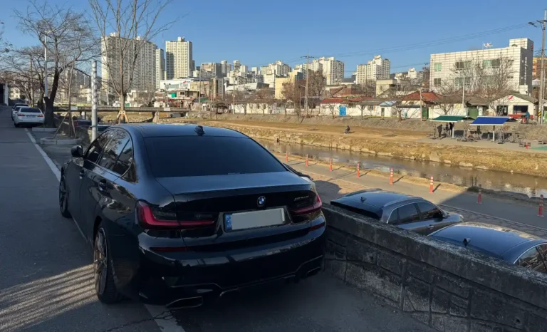 도심 하천 옆에 주차된 BMW M340i 후면 모습, 사회초년생 첫차에 대한 경험을 담은 글의 대표 이미지