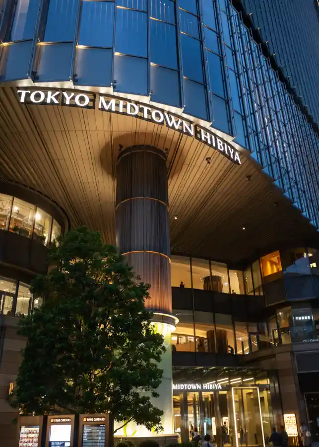 도쿄 미드타운 히비야 건물 야경, 저녁 조명이 켜진 곡선형 외관과 TOKYO MIDTOWN HIBIYA 간판