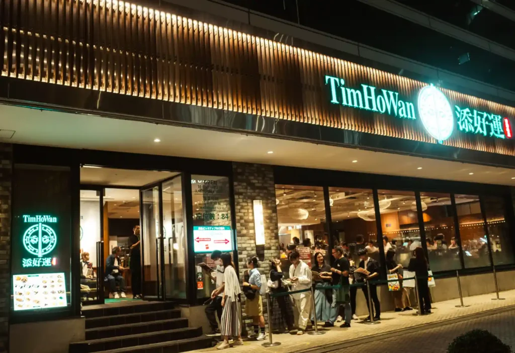 팀호완 히비야점 야간 외관, 입구 앞 웨이팅 줄과 TimHoWan 네온 간판
