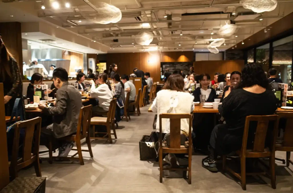 팀호완 히비야점 실내, 손님으로 가득 찬 넓은 홀과 오픈 주방