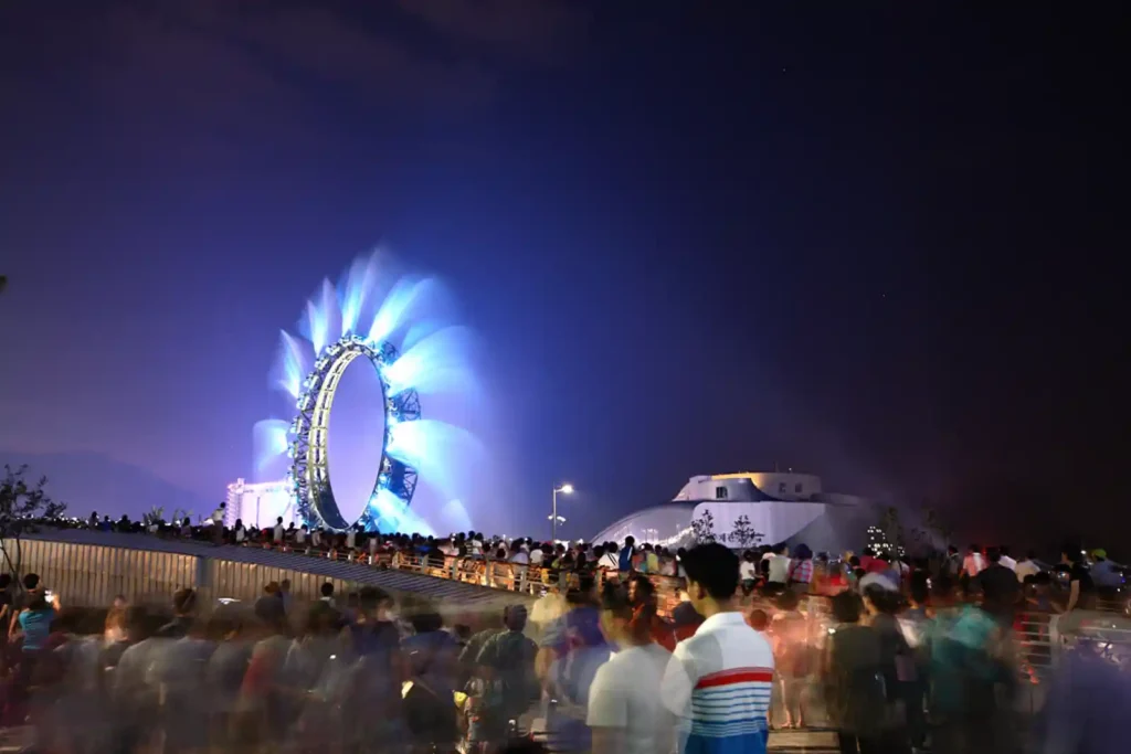 삼각대 장노출로 촬영한 야간 대관람차와 흐릿하게 번진 군중, 푸른 빛의 궤적이 담긴 도시 야경