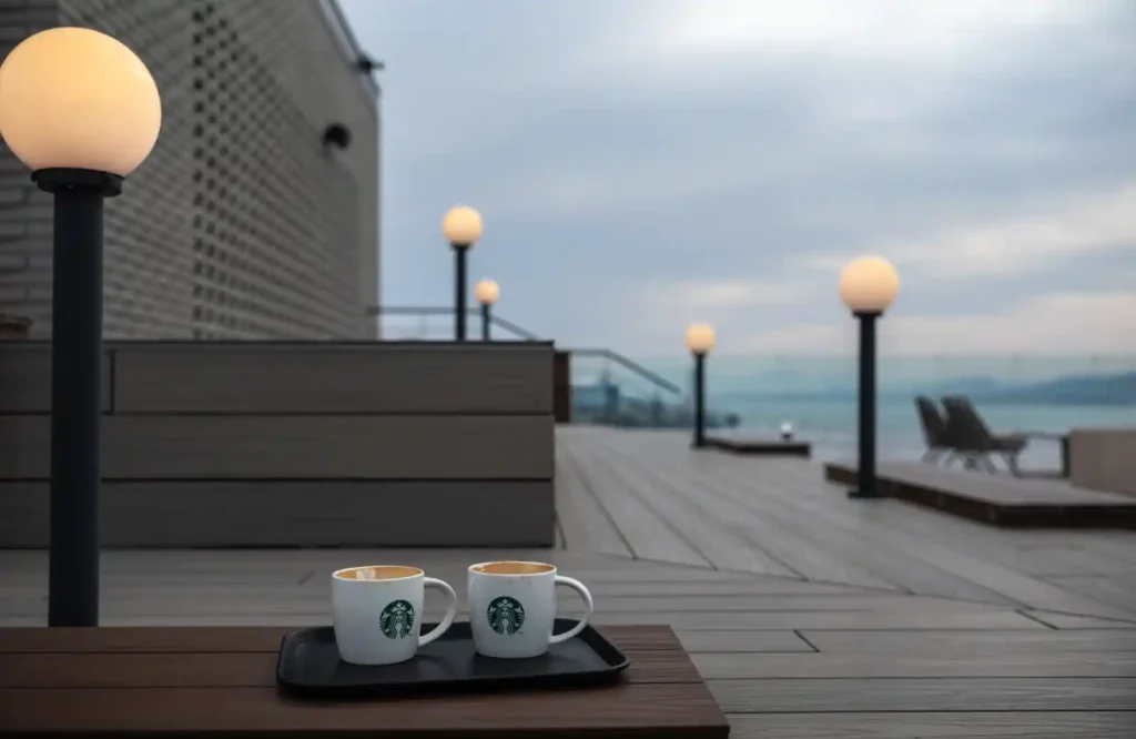 라이카 M10-R, Summilux 35mm f/1.4로 촬영한 해변 테라스 — 스타벅스 컵 두 개와 구형 가로등