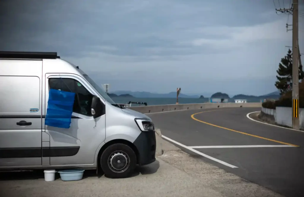 욕지도 해안일주도로 갓길에 세워진 캠핑카, 뒤로 굽어지는 도로와 한려수도 바다 풍경