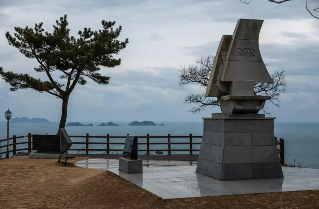 욕지도 새천년기념공원 전경, 새천년 기념 조형물과 소나무 너머로 삼여도 바위섬들이 바다 위에 나란히 펼쳐진 모습