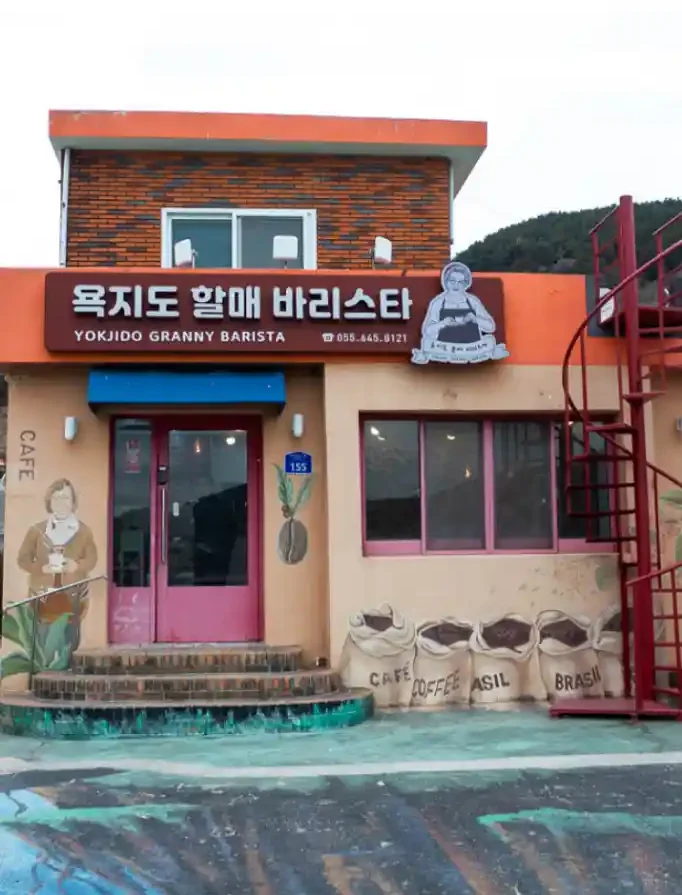 욕지도 할매바리스타 외관 전경 — 주황색 외벽과 커피 자루 벽화가 그려진 카페 건물