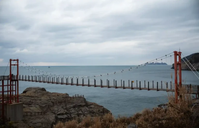 욕지도 제3출렁다리 전경, 붉은 철재 기둥과 와이어로 연결된 현수교 너머로 한려수도 바다와 섬이 보이는 겨울 풍경