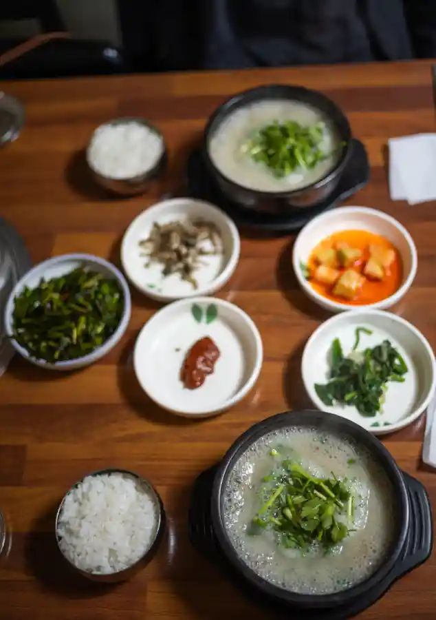 목포 조선쫄복탕 상차림, 뽀얀 국물의 복탕 뚝배기 두 개와 공기밥·밑반찬이 차려진 나무 테이블 전경