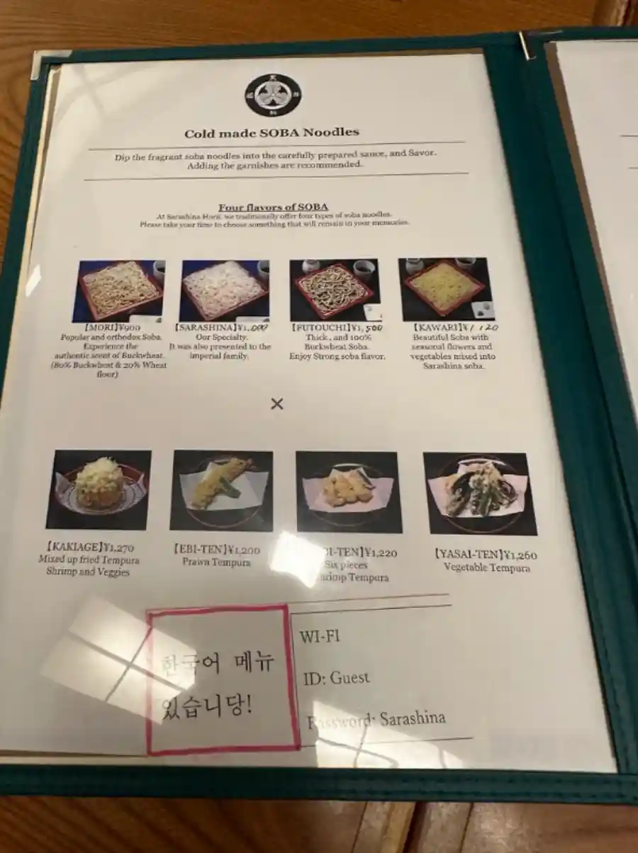 사라시나 호리이 영문 메뉴판으로, 소바 종류와 튀김 메뉴 사진이 함께 표기되어 있고 하단에 한국어 메뉴 안내 포스트잇이 붙어 있다