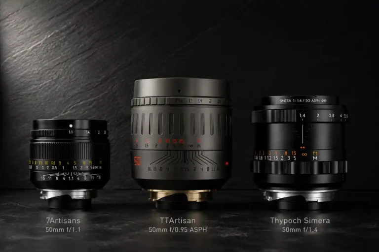 7Artisans 50mm f/1.1, TTArtisan 50mm f/0.95 ASPH, Thypoch Simera 50mm f/1.4 세 렌즈를 나란히 배치한 비교 이미지. 어두운 슬레이트 배경에 측면 조명으로 각 렌즈의 크기와 금속 질감 차이가 드러난다.