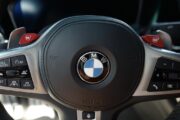 붉은색 M1, M2 버튼이 눈에 띄는 BMW M340i M 스포츠 스티어링 휠 클로즈업 사진.